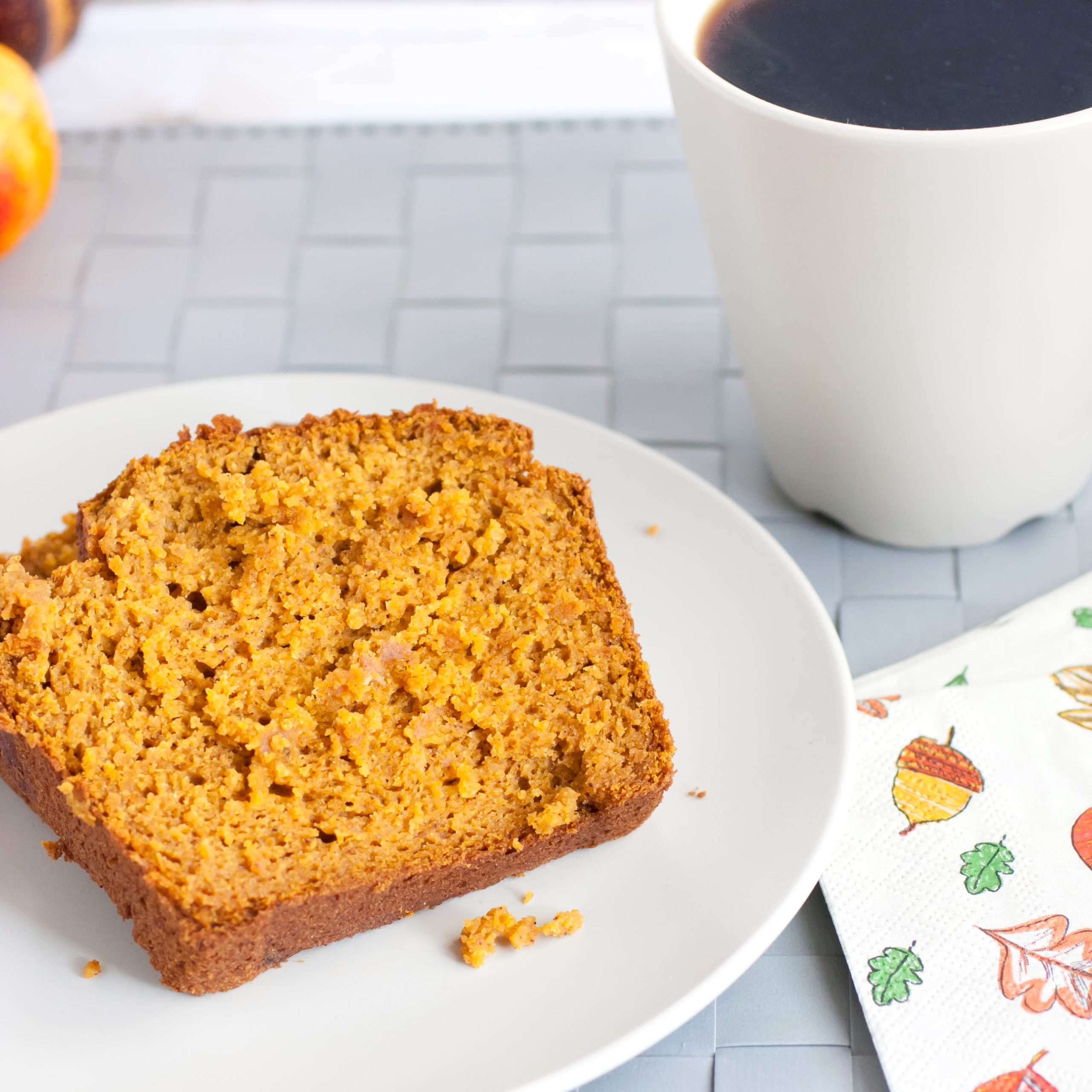Pumpkin bread on a plate with a cup of coffee.